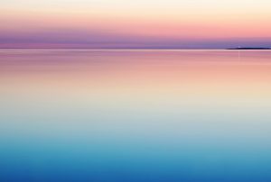 a sunset over the ocean with a small island in the distance