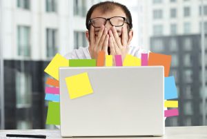 a man sitting in front of a laptop with sticky notes on it