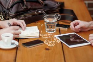 a glass of water with a straw and a drawing of lemons that says lemons into lemonade