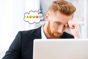 a man sitting in front of a laptop with a thought bubble with emojis on it