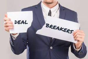 a man in a suit is ripping a piece of paper that says dealbreakers