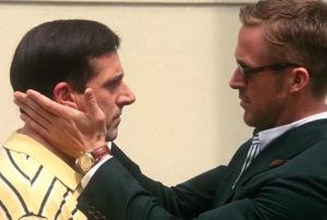 a man in a green suit touches another man's face