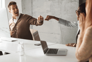 a group of people sitting around a table with a laptop