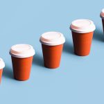 en rad röda kaffekoppar med vita lock mot en blå bakgrund