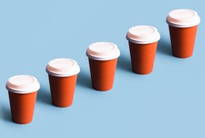 a row of red coffee cups with white lids on a blue background