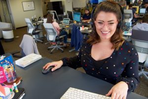 a person wearing headphones sits at a desk in an office