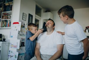 two kids are playing with a person's beard