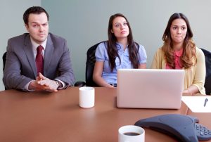 a man and two women sit at a table with a laptop