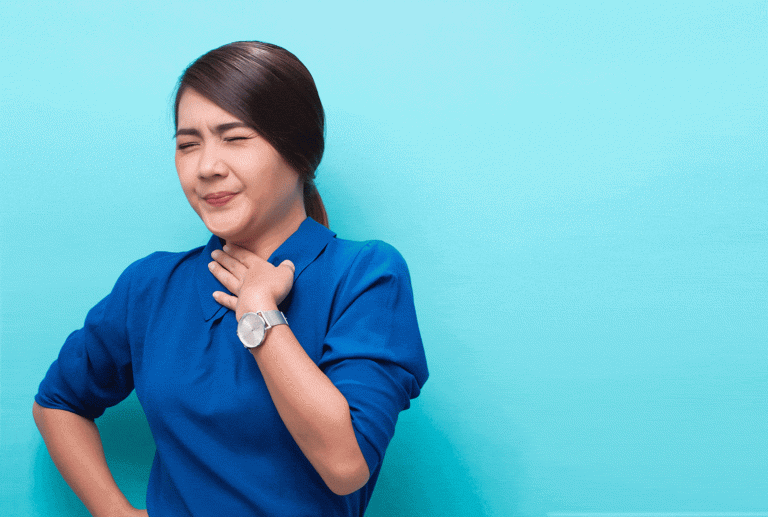 a woman in a blue shirt is holding her throat and wearing a watch