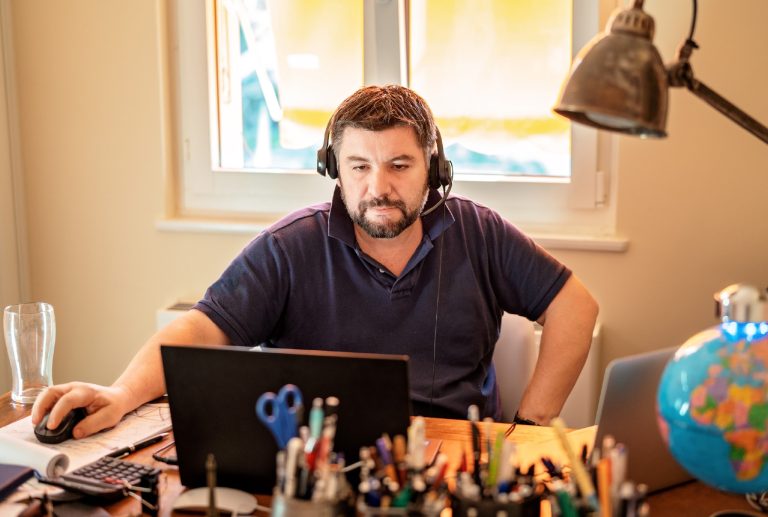 a man wearing a headset looks at a laptop