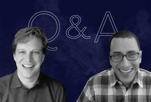 Guy Suter and Ben goldstein smiling in front of a blue background with q & a written on it