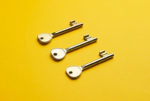 three keys are lined up on a yellow surface