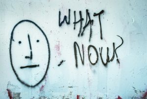 graffiti on a wall that says what now