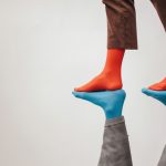 a person wearing red socks stands on top of a reflection wearing blue socks
