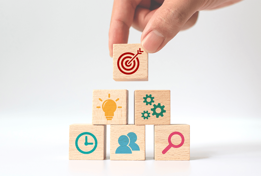 a hand holds a wooden block with a target on it and add it to a stack of wooden blocks