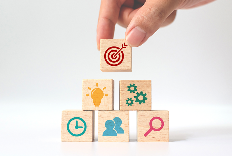 a hand holds a wooden block with a target on it and add it to a stack of wooden blocks