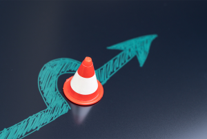 a red white and blue traffic cone sits as a flue arrows goes around and past it