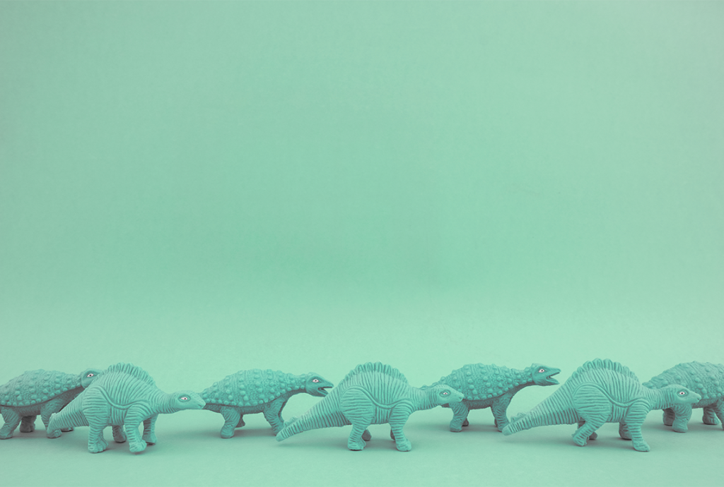 a row of toy dinosaurs on a green background