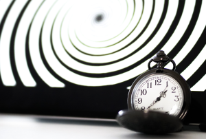 a pocket watch is sitting in front of an optical illusion