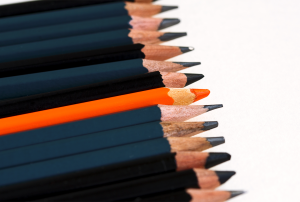 a row of black and orange pencils are lined up in a row