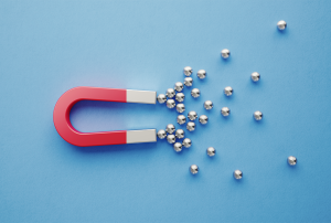 a red magnet with silver balls coming toward it