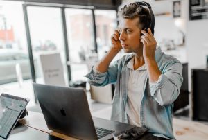 en mann med hodetelefoner sitter foran en bærbar apple-pc