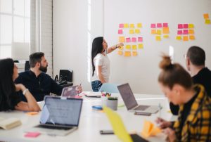 a woman is pointing at sticky notes on a white board