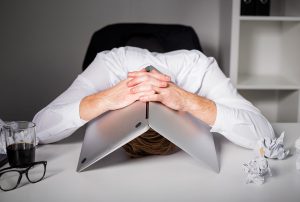 a man with his head resting on a laptop
