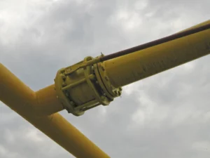 a closeup of a yellow pipe with a cloudy sky in the background