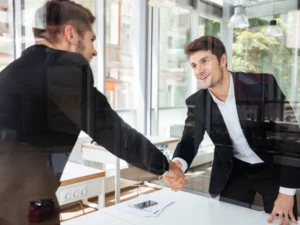 a man in a suit shakes hands with another man in a white shirt