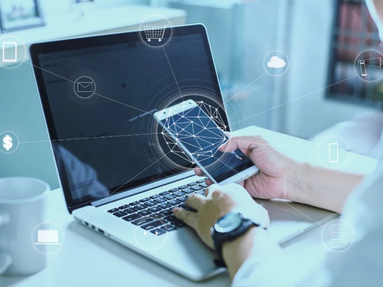 a person is using a laptop and holding a cell phone