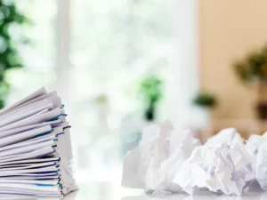 a stack of papers is sitting on a table next to a pile of crumpled paper .