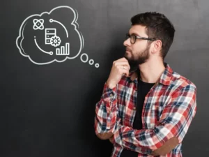 a man in a plaid shirt stands in front of a blackboard with a thought bubble drawn on it