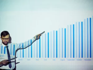 a man is giving a presentation with a graph showing a growth from march to November