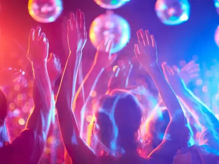 a crowd of people raising their hands in the air at a party