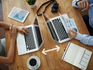 a man and a woman are sitting at a table using laptops