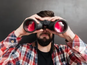 a man in a plaid shirt is looking through binoculars