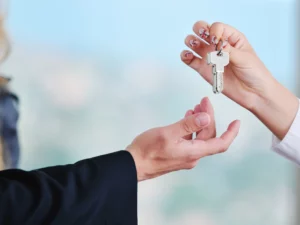 a woman is handing a key to a man in a suit