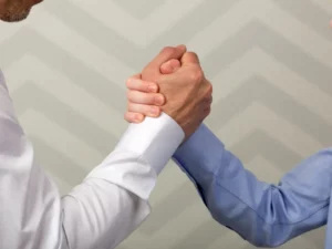 a man in a white shirt shakes hands with another man in a blue shirt
