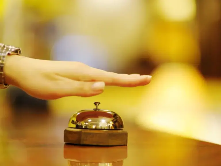 a hand is pressing a bell on a table