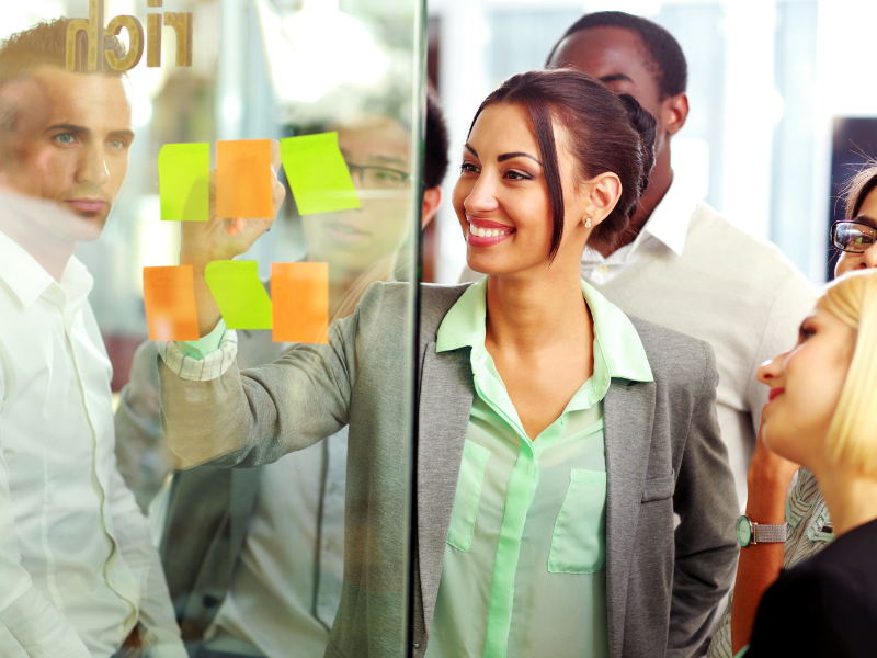 a group of people are looking at sticky notes on a glass wall with the word doin written on it