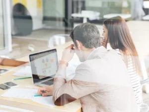a man and woman looking at a laptop