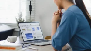 a lady looking a the screen of a laptop showing reports through graphs