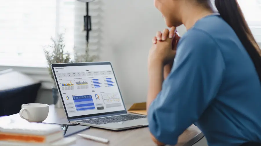 en dame kigger på skærmen på en bærbar computer, der viser rapporter gennem grafer