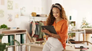 a lady inside a small business shop is sitting on a table and using a tablet