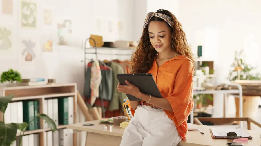 a lady inside a small business shop is sitting on a table and using a tablet